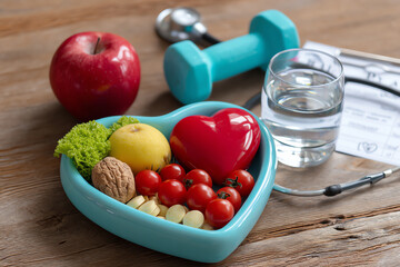 Heart-shaped bowl filled with healthy foods, surrounded by a dumbbell, stethoscope, glass of water, and an apple, symbolizing wellness and heart health
