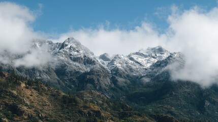 Majestic mountain peaks covered in snow and clouds. Scenic cold landscape with rocky terrain and trees for travel banner.
