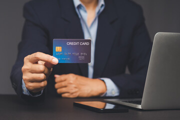 Businessman holding credit card near laptop showing online banking or e-payment.