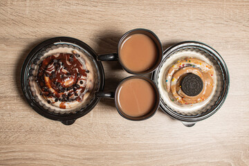 Top view of two cinnamon buns with two cups of hot coffee