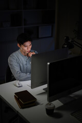 Serious male employee working overtime on desktop computer