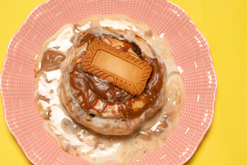 A fresh cinnamon bun with biscuit topping on a pink plate