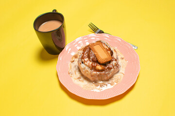 A breakfast scene with a cinnamon roll and a cup of hot coffee