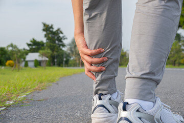 Asian man with acute ankle pain during morning jog on paved path, possible sprain or strain....