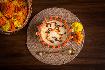 Vermicelli pudding/Kheer on brass bowl with marigold flowers on background.