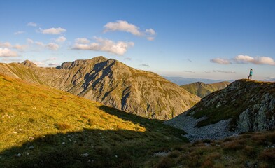 Hiker standing on mountain ridge with scenic alpine view at sunset