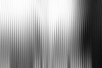 A textured background with vertical ribbed lines, transitioning from bright white light on the left to dark shadow on the right, creating a dramatic abstract pattern