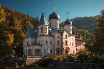 Fototapeta premium Holy Trinity Monastery nestled in the mountains, showcasing stunning architecture against a backdrop of autumn foliage and clear blue skies
