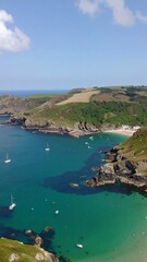 Fototapeta premium Serene coastal scene, turquoise waters, verdant hills, several sailboats