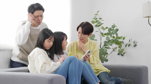 スマホを見ながら困った表情の小学生の女の子の家族
