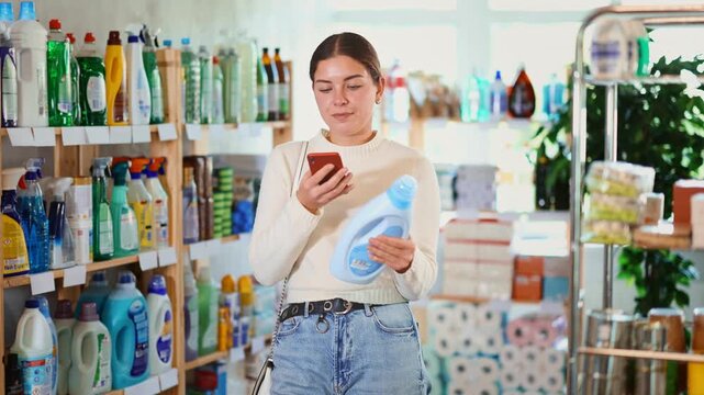 Woman is holding a phone in her hands and scanning the qr code of a home and kitchen cleaner. Customer pays a stain remover on an online app on a mobile. High quality 4k footage