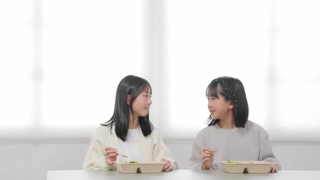 食事、子供、宅食、宅配、女の子、小学生、料理、食べる、デリバリー、弁当、給食、フードデリバリー、子ども食堂、笑顔、食卓、友達、仲良し、姉妹、ランチ、出前、ボックス、テイクアウト、食育、安心、安全、ボランティア、支援、サポート、サービス、フード、グルメ、コピースペース、広告、教育、弁当箱、ケータリング、児童、女子、教室、調理実習、会話、ポジティブ、元気、明るい、テーブル、配達、食堂、日本人、人物