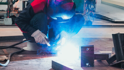 A skilled welder is intensely focused on joining metal pieces together. The bright light and sparks...