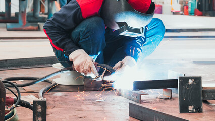 A skilled worker uses a welding torch to join metal pieces together in a workshop. Sparks fly as...