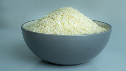 A bowl filled with fluffy, freshly prepared white rice sits on a plain surface. The rice appears warm and inviting, perfect for serving with various cuisines