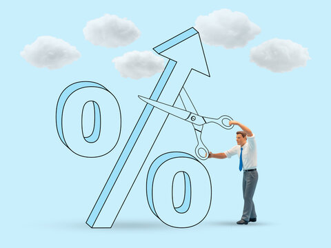 Miniature Businessman cuts rising percentage—symbolizing reduced interest rates or financial intervention.