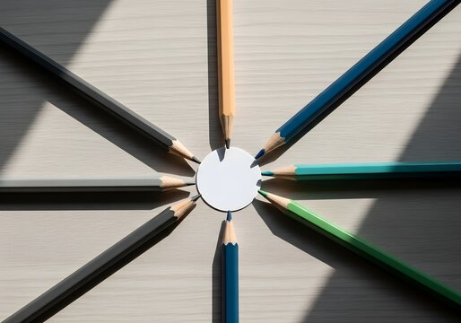Top-down photo of pencils aligned and pointing toward a center circle, abstract minimalist concept representing unified teamwork and direction