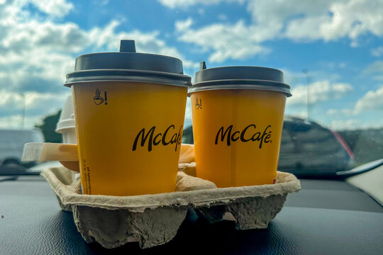 Malopole, Poland Two takeaway McCafe cups rest on vehicle dashboard with bright cloudy sky seen through windshield