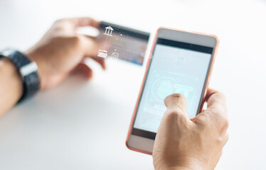 Hands using smartphone and credit card for secure mobile banking transaction with digital interface icons, representing online payment and financial technology.