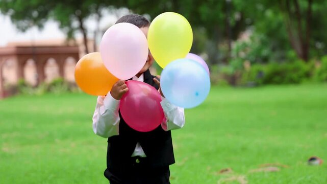 little indian birthday kid dressed up with awe expression and balloons in daylight