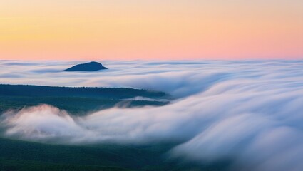Misty mountain peak emerging from a sea of clouds at sunrise