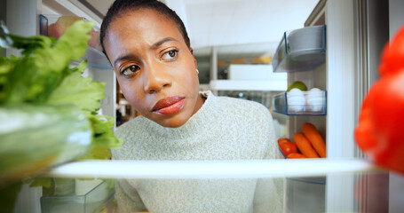 Woman, thinking and hungry at fridge in home, choice and options with vegetables for meal. African...