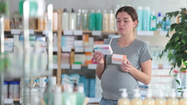 Pregnant woman buys toxicosis pills at a pharmacy. Woman chooses cold pills that can be used by pregnant women. High quality 4k footage