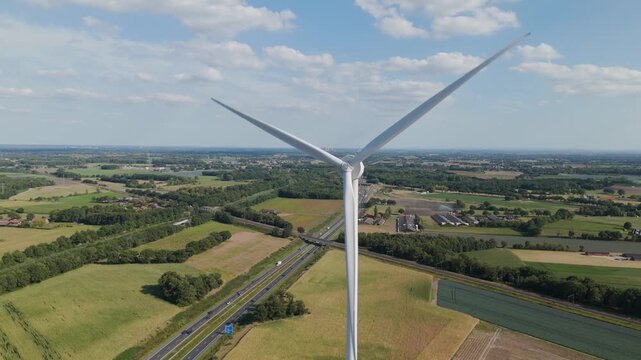 Scenic aerial footage of a wind turbine generating renewable energy in farmland countryside in the Netherlands.