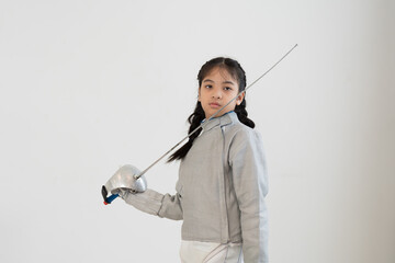 Asian girl in fencing costume and holding sword for practicing and training in gym. Teen girl...