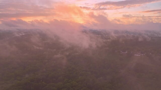 Soaring through low-hanging clouds and heading towards a pink and yellow sunset while also passing over an RV park in Branson, Missouri.