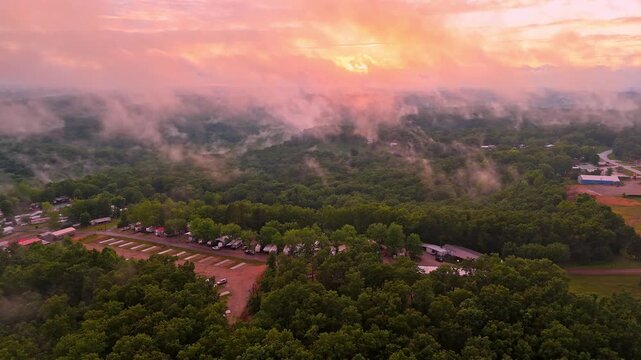 Wispy clouds hang low over an RV park in Branson, Missouri as a sunset brightens the sky in the background.