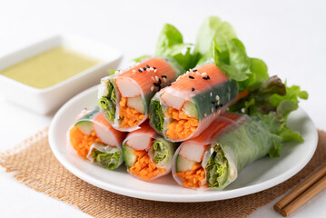 Salad roll with crab stick, carrot, cucumber and lettuce wrapped with rice paper eating with dipping sauce