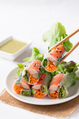Salad roll with crab stick, carrot, cucumber and lettuce wrapped with rice paper eating with dipping sauce