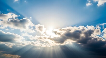 Sunlight streams through clouds, illuminating the vast blue sky
