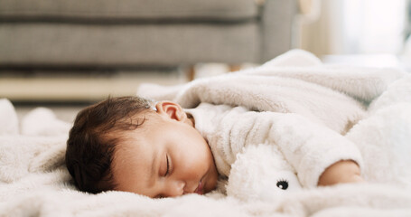Baby, teddy bear and sleeping on blanket in home for resting, morning routine or child development....