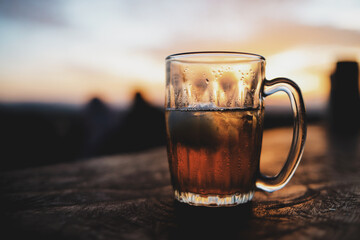 Glass of beer on table with sunset background
