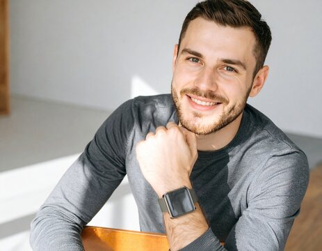 Happy Young Man Smiling Confidently at Home Office, Wearing Smartwatch