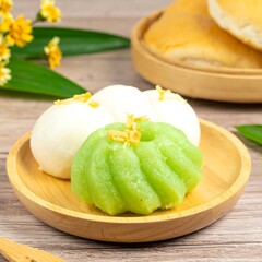 Two pastel-colored desserts on a small wooden plate, accompanied by bread and flowers