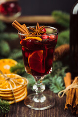 Glass of mulled wine with cranberry, citrus fruit and spices. Hot winter drinks in christmas environment. Cozy winter mood.