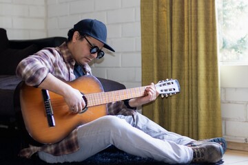 a latino man sitting on the floor playing the guitar