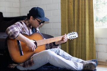 a man sitting on the floor playing the guitar