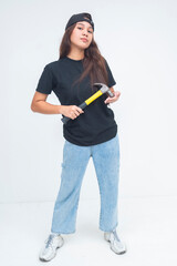 Confident young boyish woman holding a hammer at her side while looking bold and self-assured....