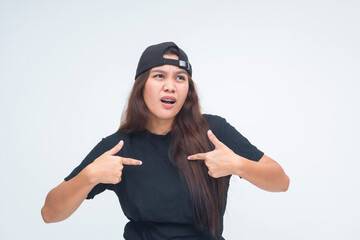 Confused and dumbfounded young boyish woman pointing at herself with a doubtful expression, as if...