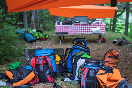 Colourful camping gear and barrels under tarp at forest campsite