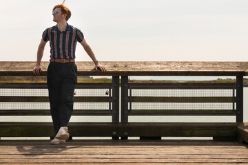 Young man enjoys sunny day on wooden pier with scenic water