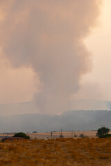 A Massive Plume of Smoke Rising from a Wildfire in Distant Hills
