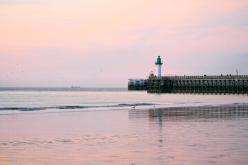 An old lighthouse on a wooden jetty on the English Channel. View of the Atlantic coast in the evening.
