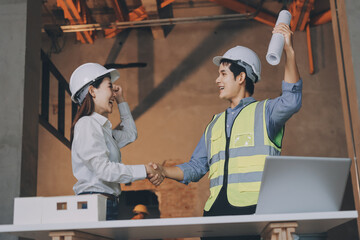 Construction manager and engineer dressed in orange work vests and hard helmets explore...