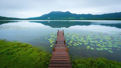 Fototapeta premium Wooden Pier Extending into a Calm Lake with Mountains