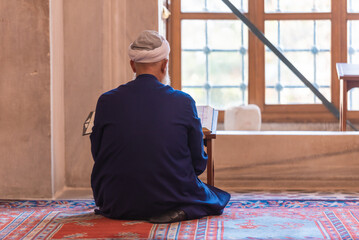 a believer reads the holy scripture, an imam in a mosque reads the Koran